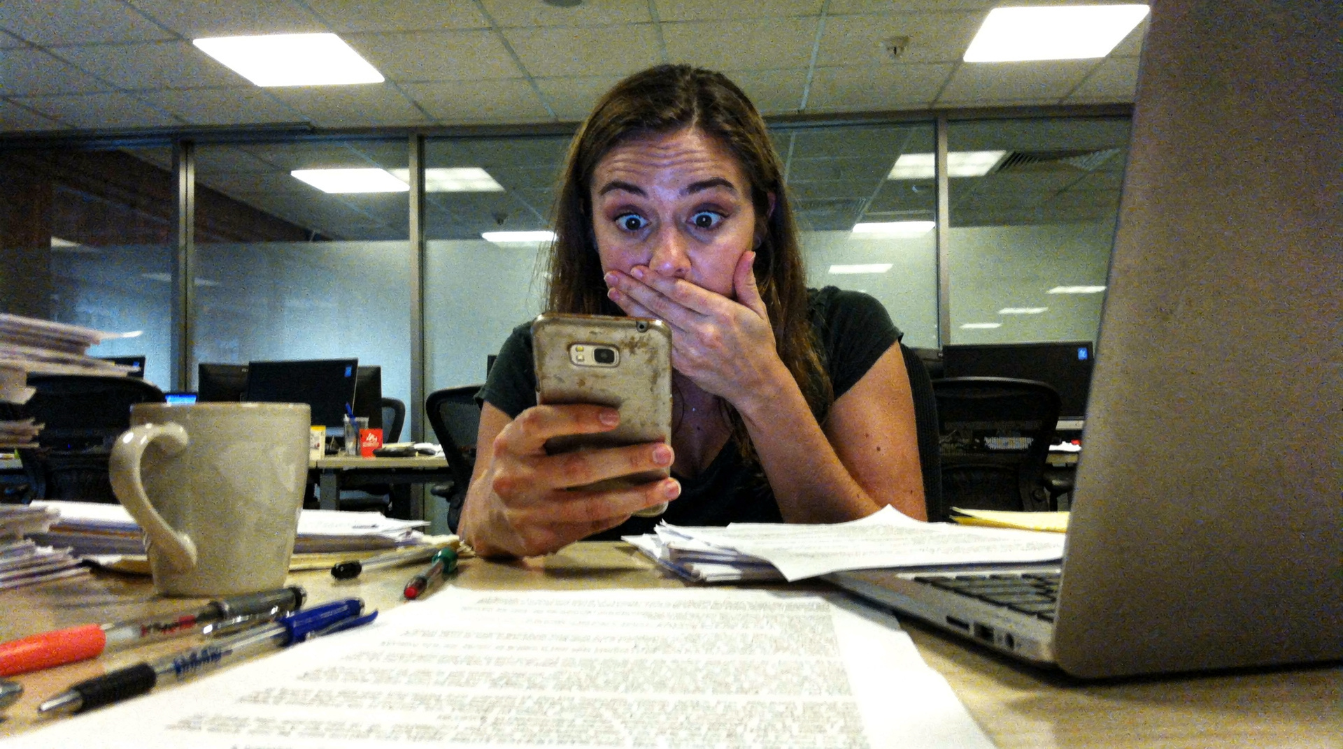 A woman looking at her phone with a surprised expression